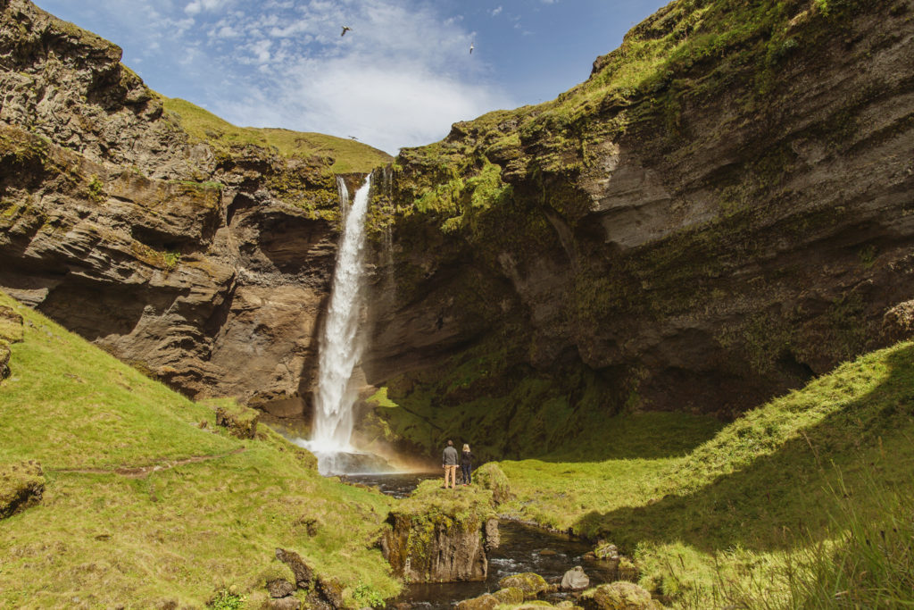 Couple at Kvernufoss Waterfall in Iceland Adventuring during their engagement session
