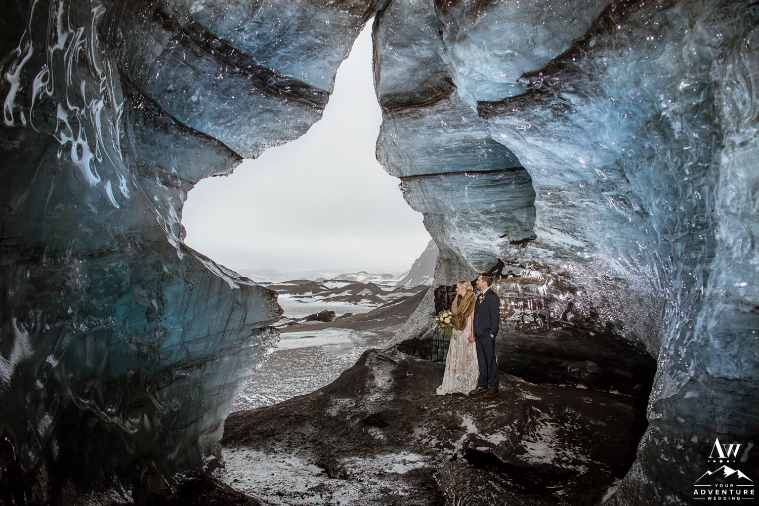 Couple standing in the opening of an ice cave