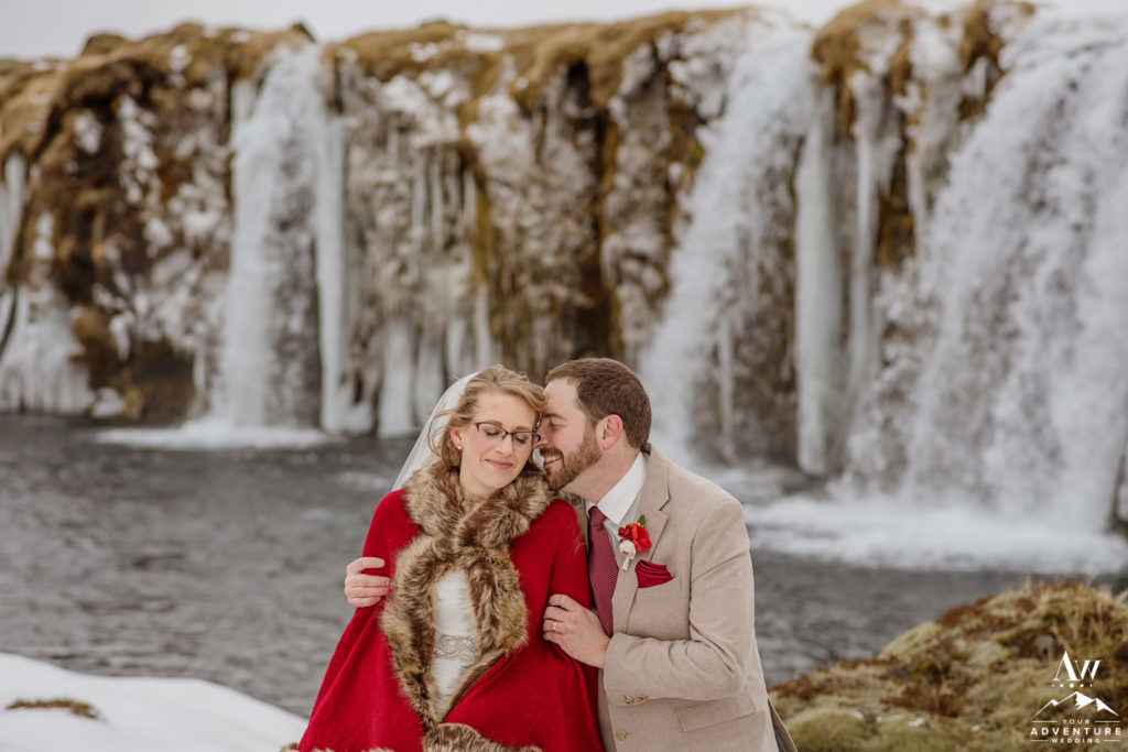 Iceland wedding couple cuddling in front of a waterfall