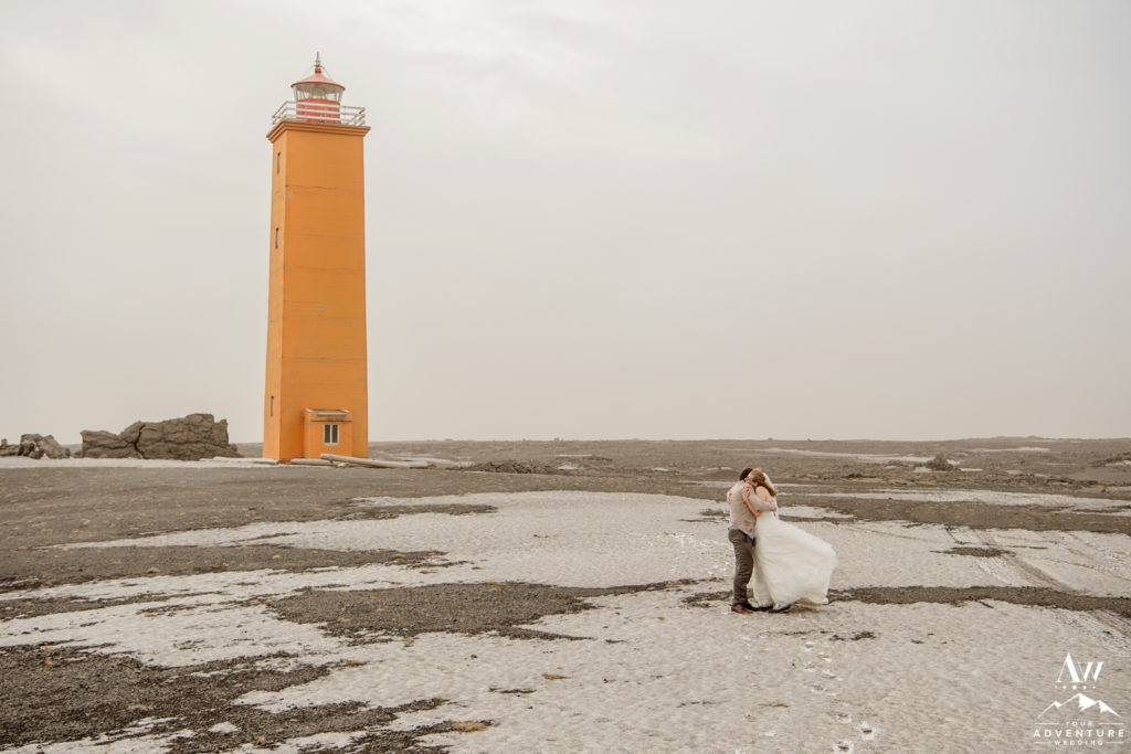 Couple hugging in front of a Lighthouse in Iceland