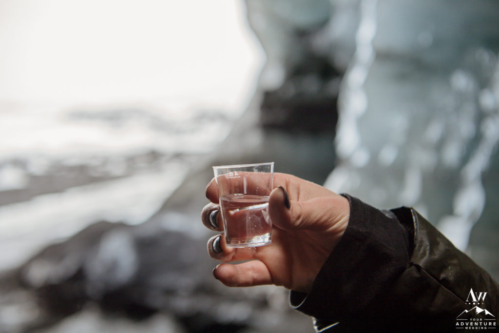 Iceland wedding couple taking a shot of black death in an ice cave