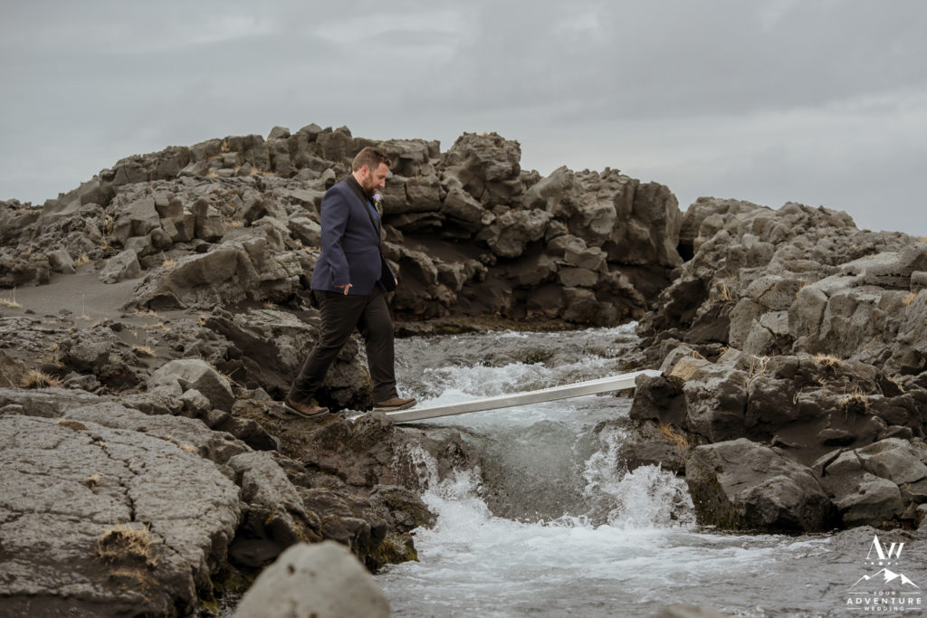Groom crossing a bridge during Iceland wedding adventure
