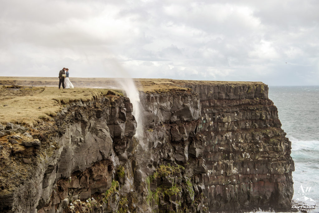 Iceland Elopement Couple kissing on top of golden sea cliffs