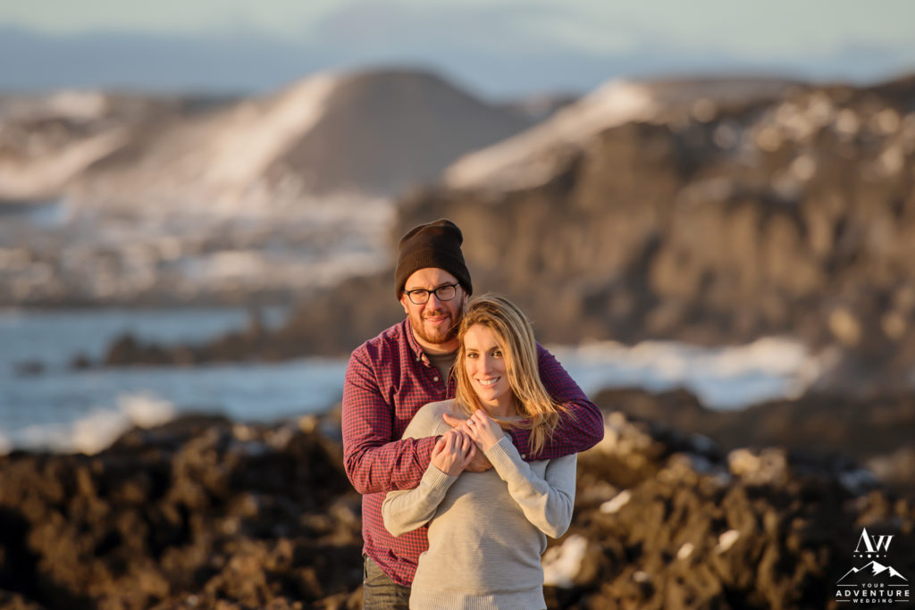 Iceland Engagement Photo with couple looking at the camera and mountains behind