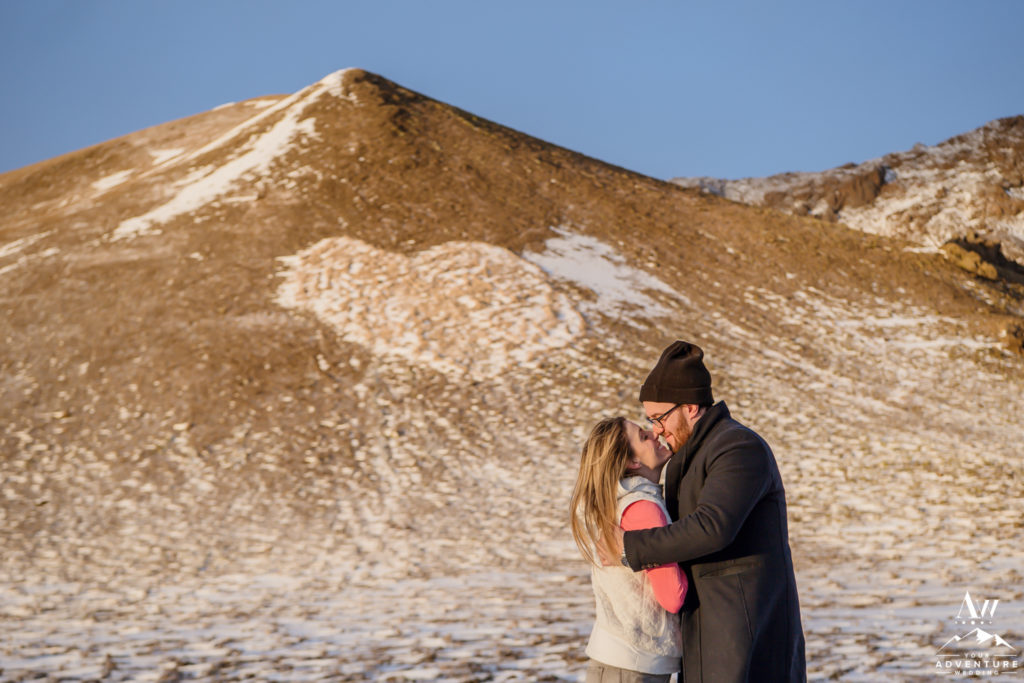 Couple kissing in front of heart shaped mountain in Iceland