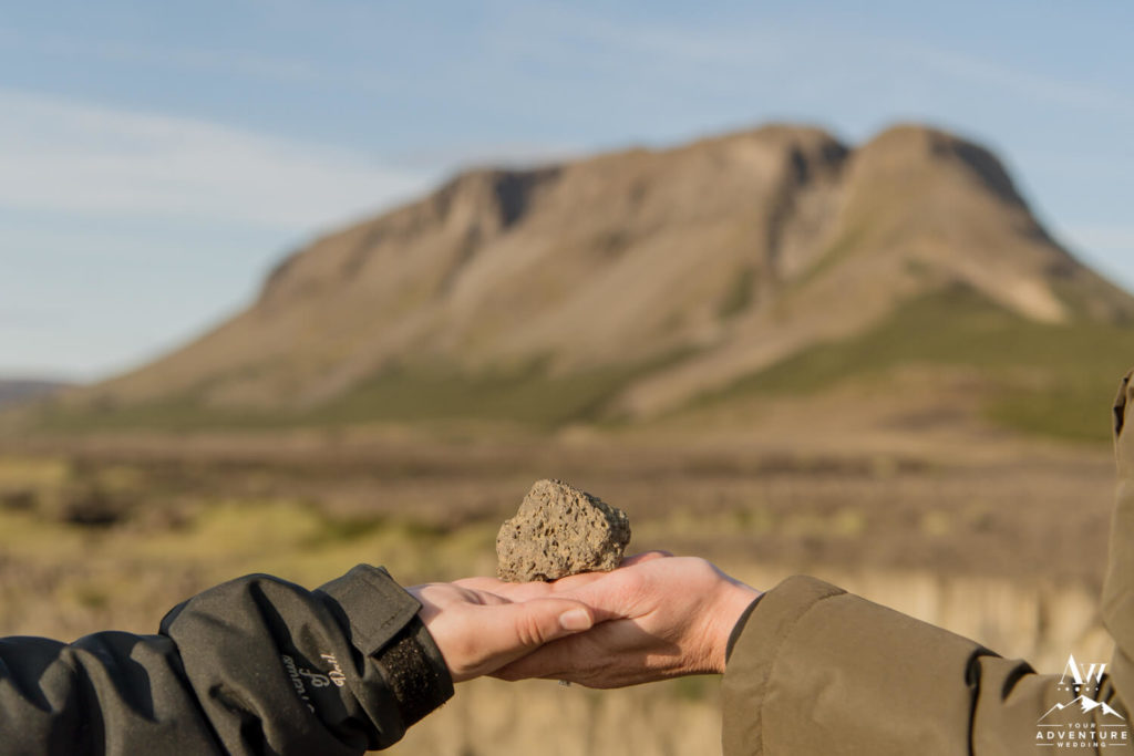 Iceland Proposal Couple holding a rock with mountain behind