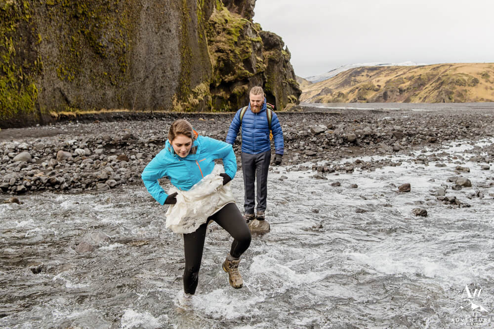 Iceland Wedding Couple Hiking through River on Stakkholtsgjá Hike